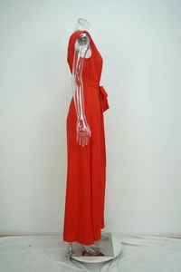 Detail of red sleeveless jumpsuit showing the waist tie bow and side profile cut