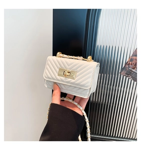 Detailed close-up of white chevron quilted bag with golden twist lock and chain strap