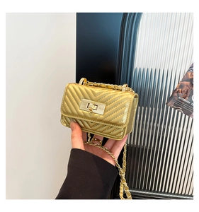 Close-up of a gold mini chain bag featuring V-shaped quilting and a metal turn-lock