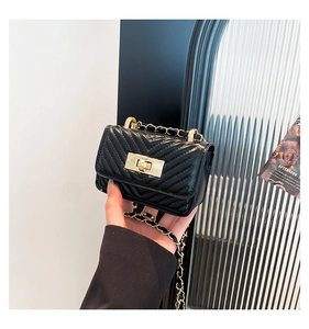 Close-up of black quilted mini square bag with gold hardware and chain strap