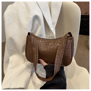 Détail de la texture tressée marron d'un sac à bandoulière porté par un mannequin