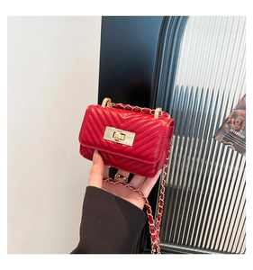 Detail of red quilted leather mini crossbody bag with golden chain and clasp being held