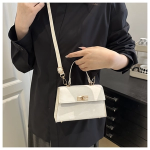 Detail view of a white mini crossbody bag featuring a glossy finish and gold turn-lock closure