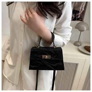 Détail d'un sac à main noir en similicuir plissé avec un fermoir rotatif doré