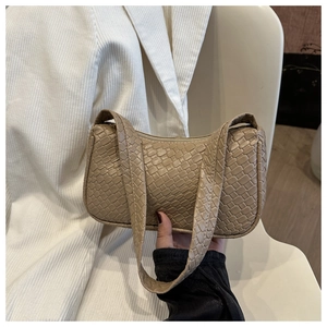 Détail de la texture tressée kaki et de la bandoulière élégante sur le sac à main