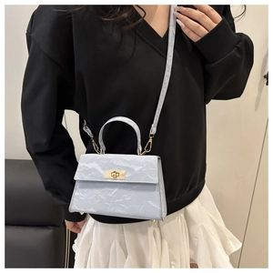 Detail of light blue crossbody bag with marble texture and golden metal twist lock