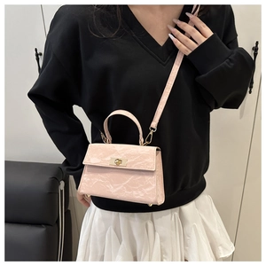 Détail d'un sac bandoulière rose texturé avec fermoir doré et bandoulière amovible