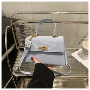 Detail of light blue pleated handbag showing textured fabric and golden metal twist lock