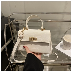 Detail of white marble pattern crossbody bag with golden metal twist lock and top handle