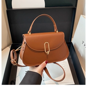 Detailed view of a brown vintage shoulder bag with golden oval lock and handle