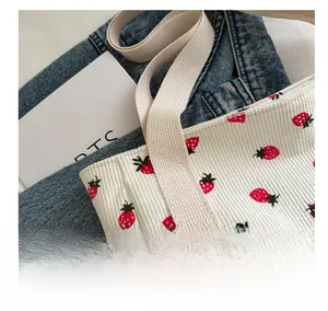 Detalle del bolso tote de pana blanca con estampado de fresas y asas de algodón
