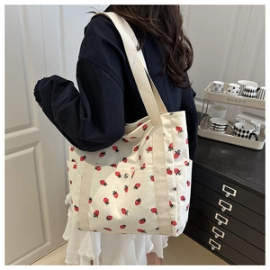 Detalle del bolso tote de pana blanca con estampado de fresas y bolsillos laterales