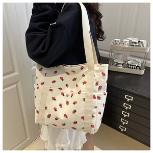 Detalle del bolso tote de pana con estampado de fresas, hebilla metálica y textura suave