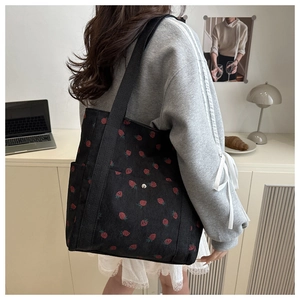 Detalle del bolso tote de pana con estampado de fresas, bolsillo frontal y asa resistente