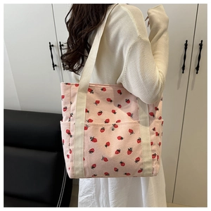 Detalle del bolso tote de pana rosa con estampados de fresas y asas de cinta crema