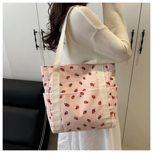 Detalle del bolso tote de pana rosa con fresas impresas y correas blancas de tela