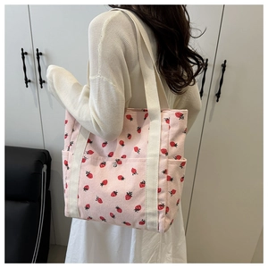 Vista detallada de bolsa tote de pana rosa con estampado de fresas y correa de hombro