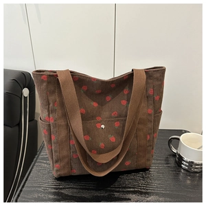 Vista detallada del bolso tote de pana marrón con estampado de fresas y cierre magnético de metal