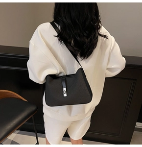 Detail of black cat-ear shoulder bag featuring diagonal embossed texture and silver lock