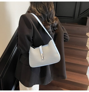 Detail of grey-blue woven shoulder bag featuring a silver metal twist lock closure