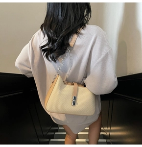 Detail of minimalist cream woven texture shoulder bag with stylish silver chain strap