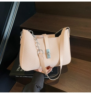 Detail of soft pink shoulder bag with diagonal texture and silver metal twist lock
