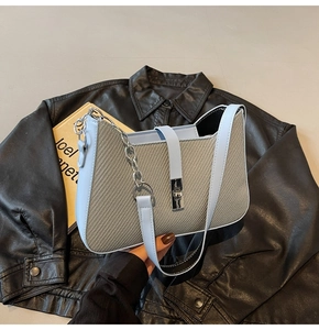 Detail of light blue and taupe patchwork handbag with metal chain strap and leather finish