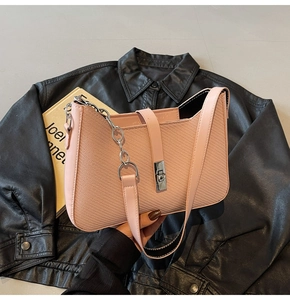 Detailed macro view of pink textured leather underarm bag with silver metallic twist lock
