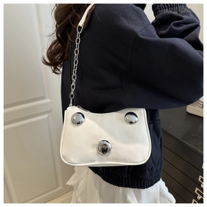 Detail view of white leather shoulder bag with silver dome studs and chain strap worn by model