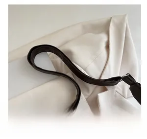 Detail of adjustable brown leather shoulder strap with silver metal buckle on a tote bag