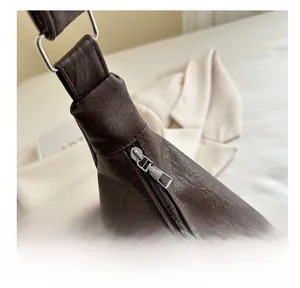 Detailed close-up of the smooth metal zipper and premium brown leather texture on a tote bag