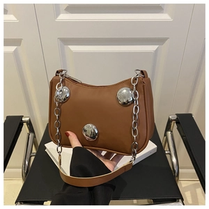 Detailed view of brown leather underarm bag featuring three large silver metal studs