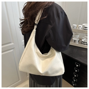 Detail of cream pebbled leather tote bag showing the half-moon shape and wide strap