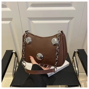 Detail of brown crescent bag featuring large silver stud accents and metal chain strap