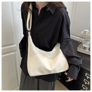 Gros plan sur le sac cabas blanc en cuir texturé porté par un mannequin au look moderne