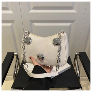 Detail of white half-moon bag featuring large silver metal spheres and chain strap