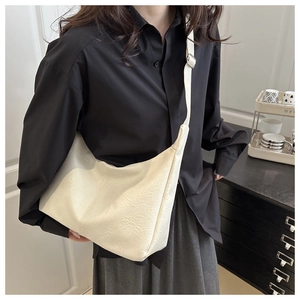 Macro shot of cream pleated faux leather tote bag with metallic strap buckle detail