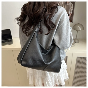 Rear view of a black oversized hobo bag showing casual drape and texture on a model