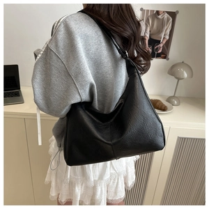 Large black textured leather hobo bag for women in a modern minimalist lifestyle setting
