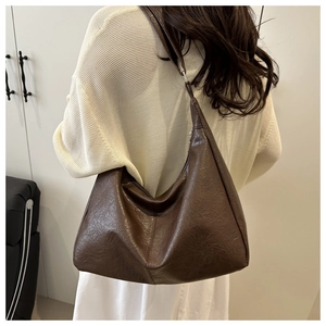 Detail of dark brown dumpling bag showing retro leather texture and adjustable strap buckle