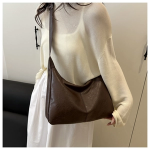 Détail de la texture en cuir PU marron foncé et large bandoulière réglable sur le sac