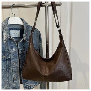 Macro detail of dark brown leather hobo bag showing zipper and vertical stitching texture