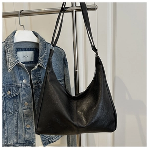 Detailed view of black litchi texture PU leather hobo bag on a metal rack