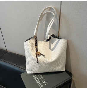 Détail du cabas blanc à texture serpent avec cordon tressé marron et cloche dorée
