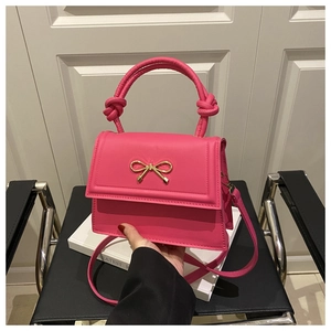 Detalle de bolso de cuero fucsia con lazo metálico y asa con nudo artesanal