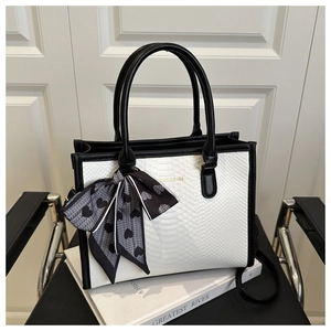 Close-up of snake skin textured handbag with heart print scarf and golden logo