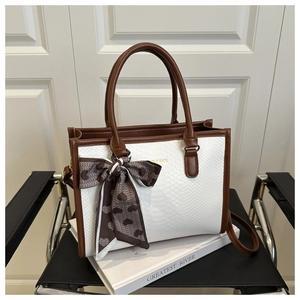 Close-up of contrast tote bag with faux snakeskin texture and heart print silk scarf