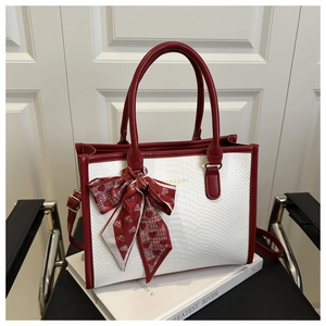 Detail of red and white snakeskin pattern handbag with silk scarf bow and gold logo
