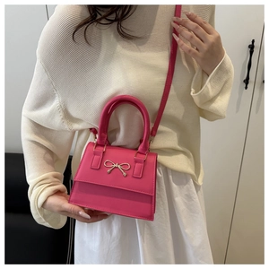 Detail of rose pink mini handbag with silver bow decoration and detachable shoulder strap