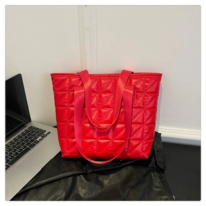 Close-up of a red quilted tote bag with rhombus stitching and spacious storage compartment